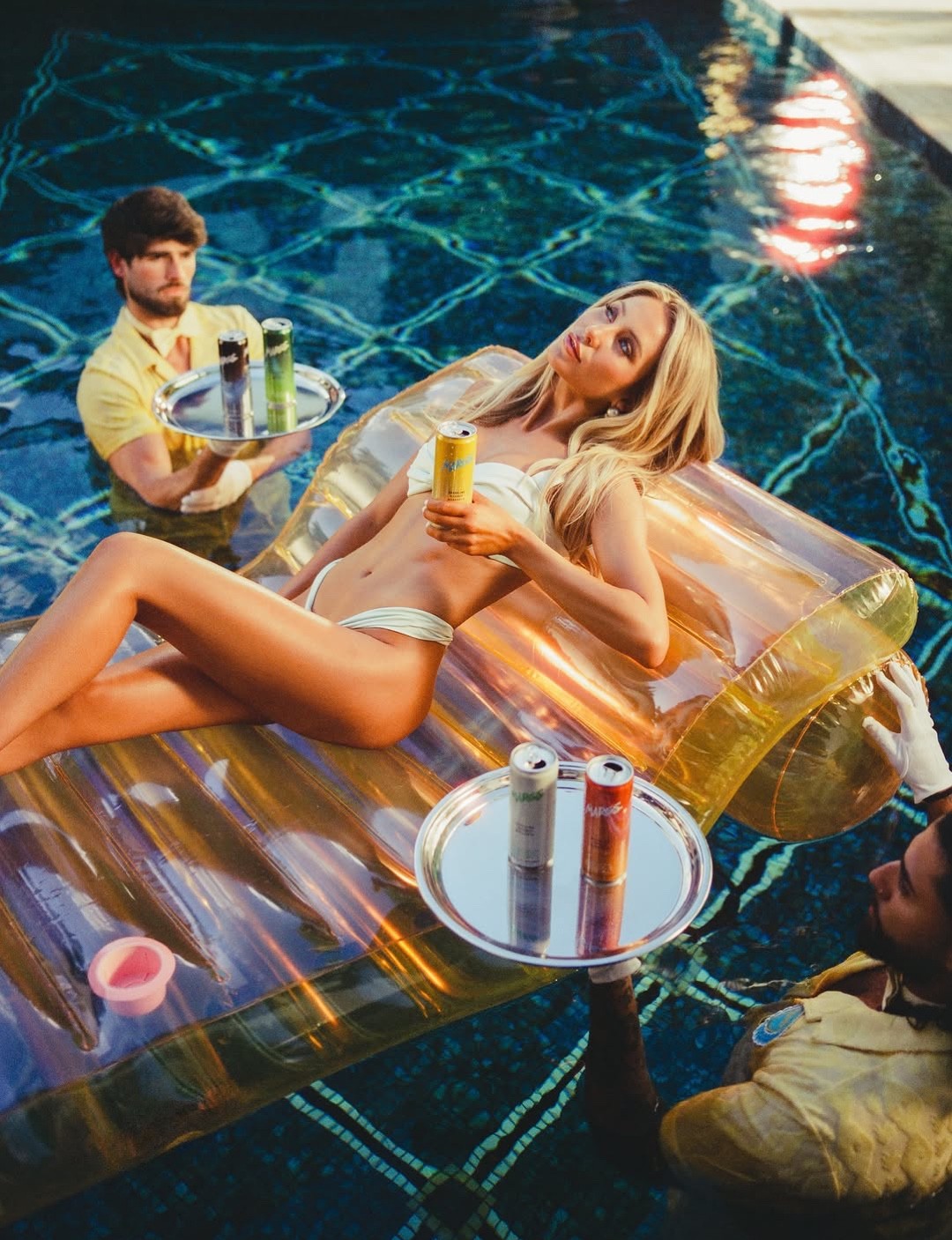 Alix Earle on a pool float surrounded by servers
